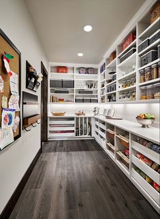 a pantry with lots of white shelves filled with food and supplies on the walls, along with wooden flooring