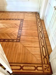 a wooden floor with an intricate design on the top and bottom edge, in a room with white walls