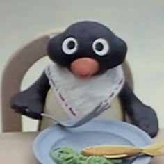 a penguin sitting at a table with a plate of food