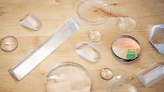 several clear objects sitting on top of a wooden table next to some scissors and other items