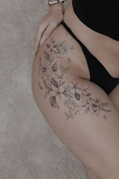 a woman's stomach with flowers and leaves tattooed on the bottom half of her body