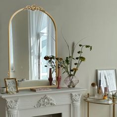 a fireplace with a mirror, vases and flowers on it