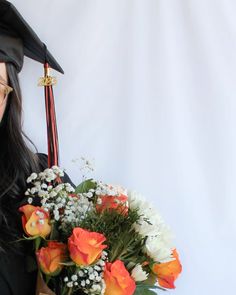 a woman wearing a graduation cap and gown holding a bouquet of flowers