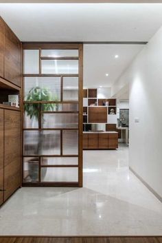 the interior of a modern home with wood and glass doors that lead to an open kitchen