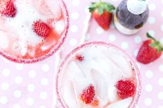 two glasses filled with ice and strawberries on top of a polka dot tablecloth