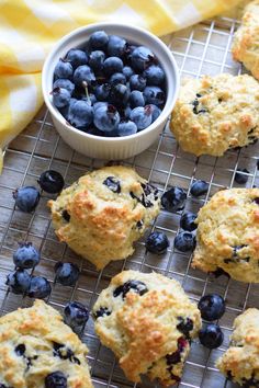 blueberry muffins cooling on a wire rack next to a bowl of blueberries