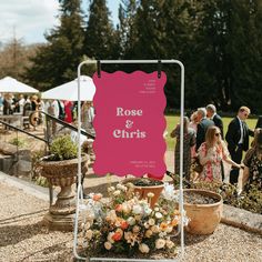 a sign that says rose and christ on it next to potted plants in front of some people