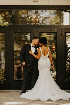 a bride and groom standing in front of a black door at their wedding reception venue