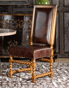 a brown leather chair sitting next to a table with a vase on top of it