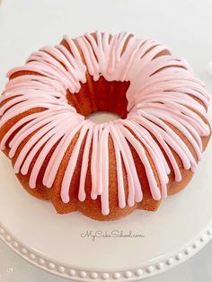 a bundt cake with pink icing on a white plate