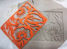 an orange and gray cutting board sitting on top of snow covered ground with cut outs