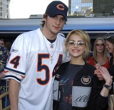 a man and woman standing next to each other in front of a crowd at a football game