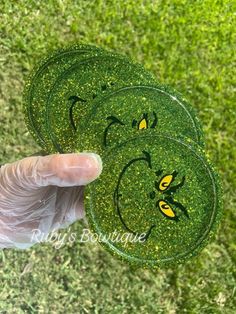 someone is holding three green coasters with yellow faces on them in the grass,