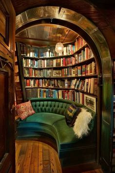 a green couch sitting in front of a bookshelf filled with lots of books