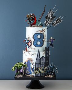 a birthday cake decorated with avengers and spider - man figurines