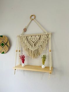 a macrame hanging on the wall next to a vase with flowers in it