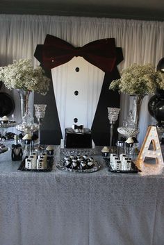 a table topped with lots of black and white desserts next to tall vases filled with baby's breath flowers