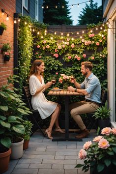 a man and woman sitting at a table with flowers on the wall in front of them