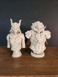 two white ceramic figurines sitting on top of a wooden table