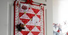 a red and white christmas quilt hanging on the wall next to a door with decorations