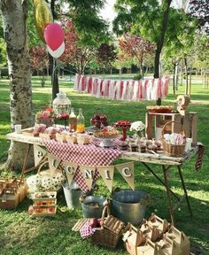 an outdoor picnic is set up in the grass with food on it and balloons hanging from the trees