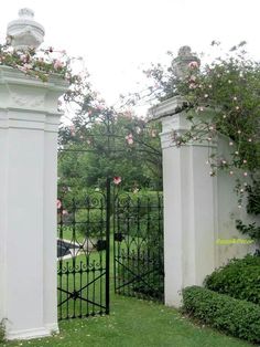 two white pillars with pink flowers on them in the middle of a green lawn area