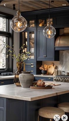 a kitchen island with stools and lights hanging from it's ceiling above it