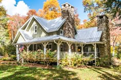 a house in the woods surrounded by trees and grass with fall foliages around it