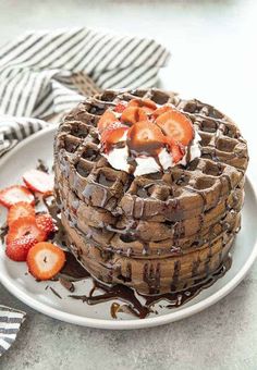 a stack of chocolate waffles with strawberries on top