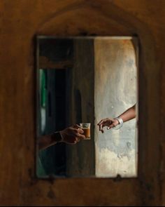 two people reaching out their hands to each other in front of a wooden wall with a mirror