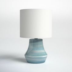 a table lamp with a white shade on it's base and a blue vase