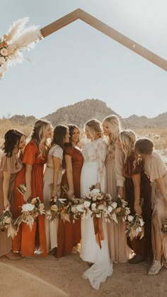 a group of women standing next to each other in front of a wooden arch with flowers