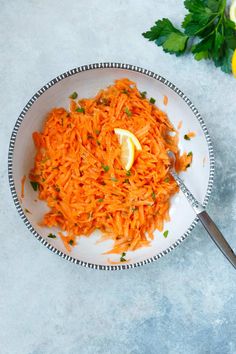 a white plate topped with carrots next to a lemon wedge and parsley on the side