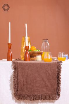 a table topped with candles and fruit on top of a white table cloth