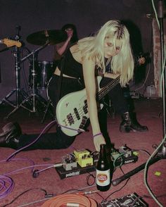 a woman kneeling on the ground with a guitar and other instruments in front of her