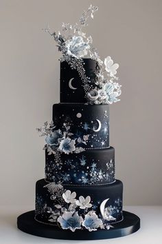 a three tiered black cake with white flowers and butterflies on it's side