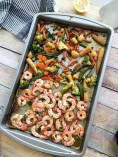 shrimp, broccoli and carrots in a baking pan on a wooden table