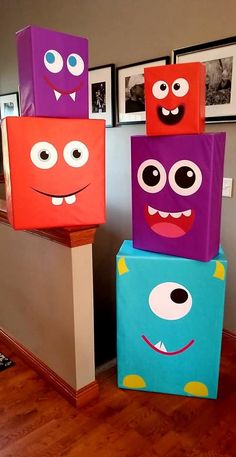 three colorful boxes with faces on them sitting in the middle of a floored room