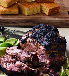 a plate with meat and vegetables on it next to some slices of cornbreads