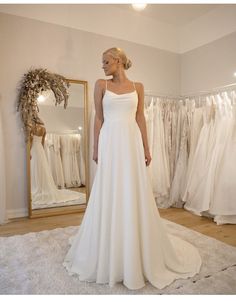 a woman standing in front of a mirror wearing a white dress