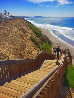 a man is walking down the stairs to the beach