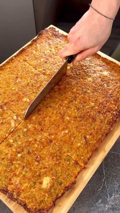 a person cutting up food on top of a wooden cutting board with a large knife