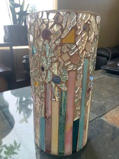 there is a vase made out of different colored glass pieces on top of a table