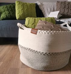 a large basket sitting on top of a hard wood floor next to a blue couch