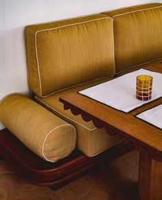 a table with two place settings on it, and a couch next to it that has a drink in the middle