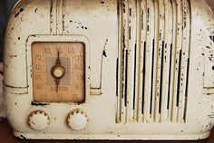 an old white radio sitting on top of a wooden table