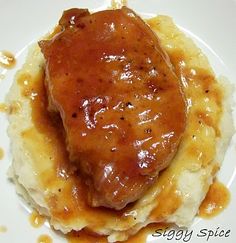 a piece of meat covered in gravy on top of mashed potatoes