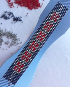 a blue comb with red letters on it sitting in the snow next to some beads