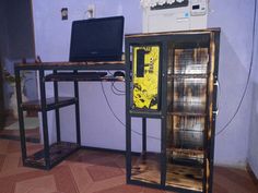 a laptop computer sitting on top of a wooden desk next to a glass case filled with books