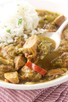 a white bowl filled with meat and vegetables next to rice